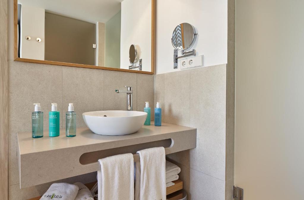 a bathroom with a sink and a mirror and towels at Can Salia in San Antonio Bay