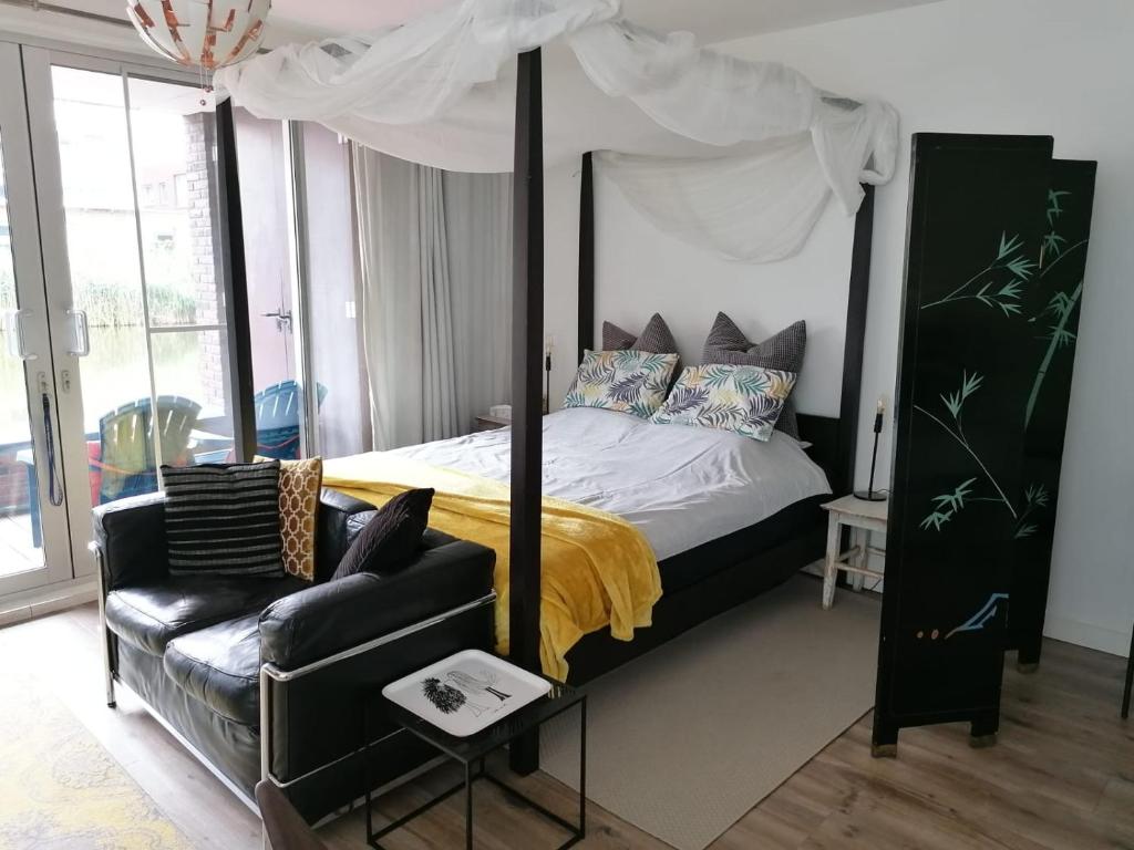 1 dormitorio con cama con dosel y sofá en The Water Studio en Ámsterdam
