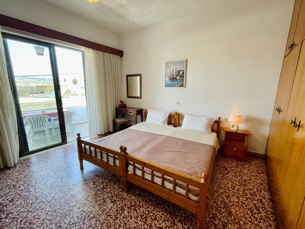 a bedroom with a bed and a large window at Afroditi Pension in Archangelos