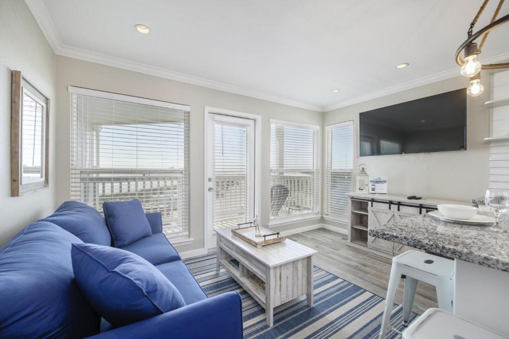 ein Wohnzimmer mit einem blauen Sofa und einer Küche in der Unterkunft Seascape 1304 Condo in Galveston