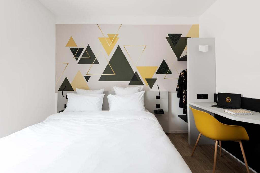 B&B HOTEL Oftringen في أوفترينجين: غرفة نوم بسرير ابيض ومكتب