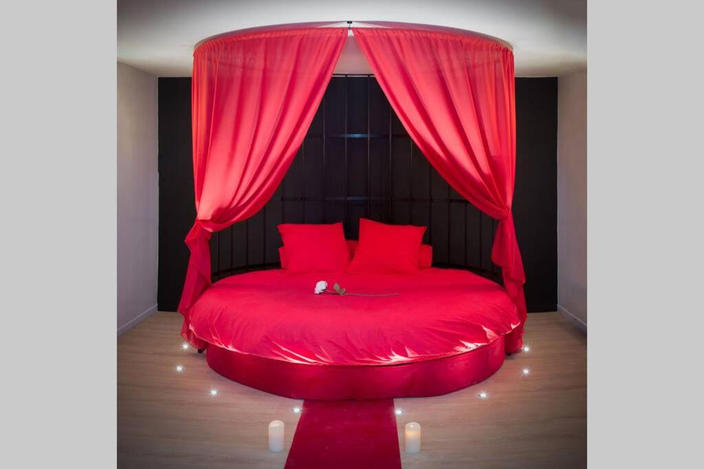 uma cama vermelha com uma cortina vermelha num quarto em LOVEROOM REIMS em Reims