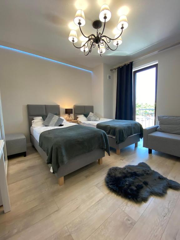 a bedroom with two beds and a chandelier at Aparthotel Riva in Zawiercie