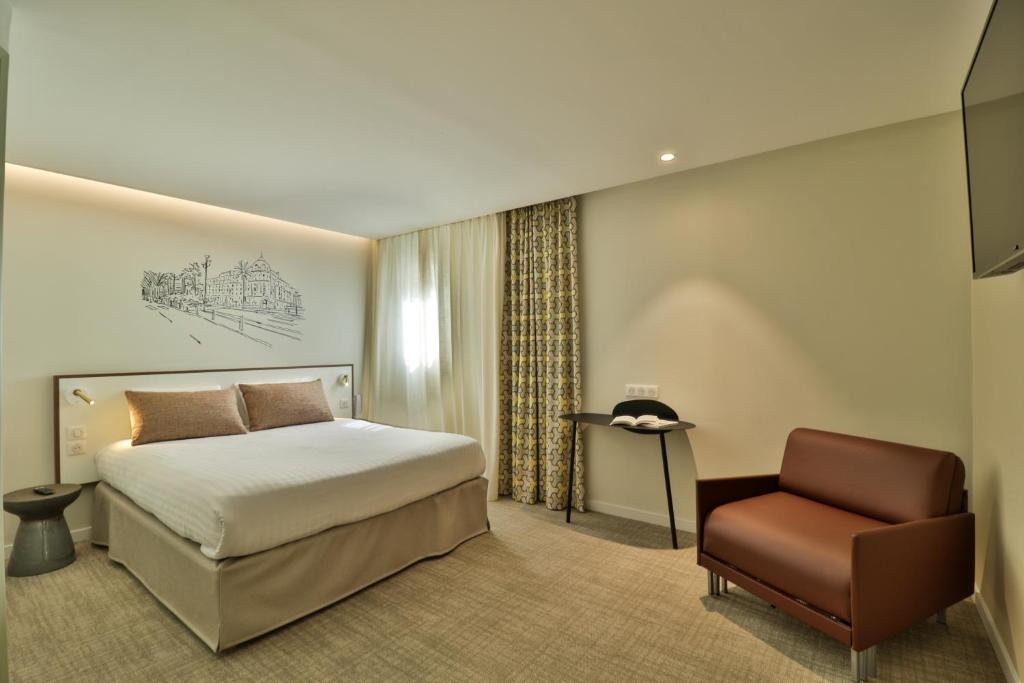 een hotelkamer met een bed en een stoel bij Hotel du Pin Nice Port in Nice