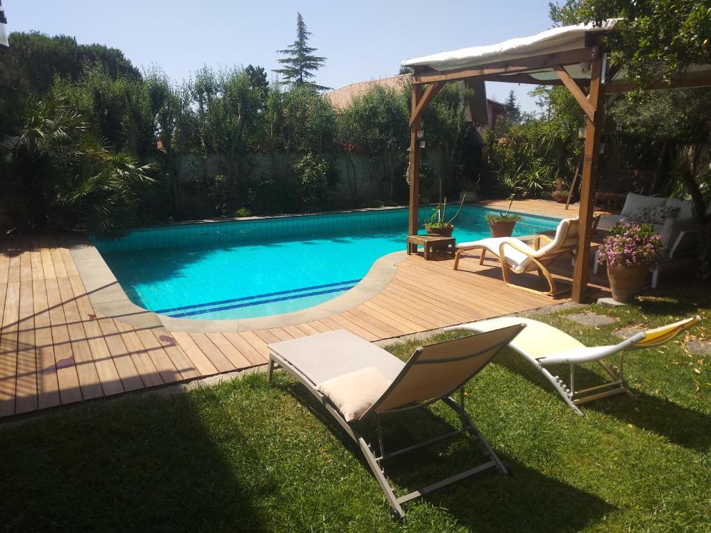 een zwembad met 2 stoelen en een prieel bij Lumia Luxury Apartments in Mascalucia