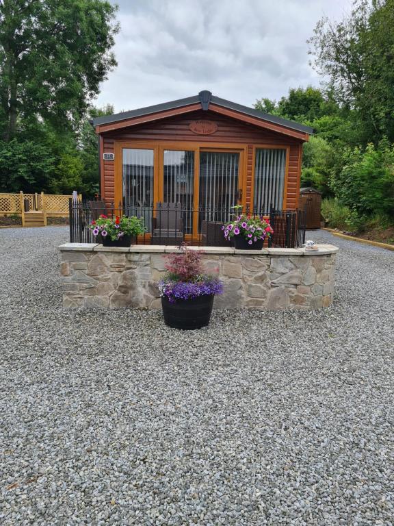 a small cabin with flowers in front of it at Bear Lodge in Auchterarder