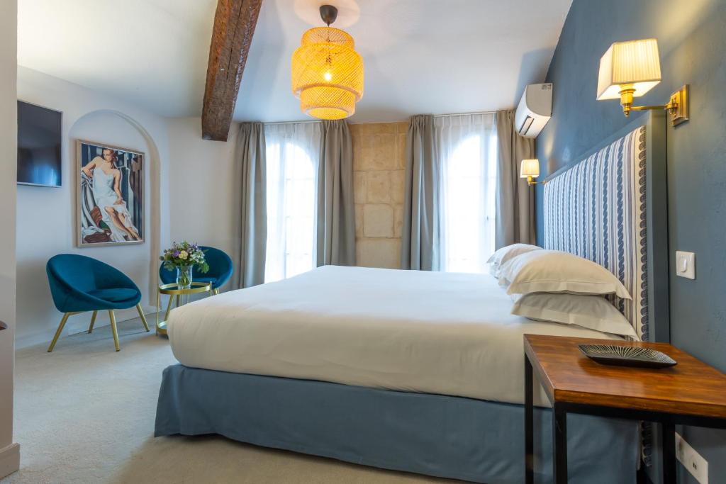 a bedroom with a large bed and a table and a desk at Hôtel Le Relais de Poste Arles Centre Historique in Arles