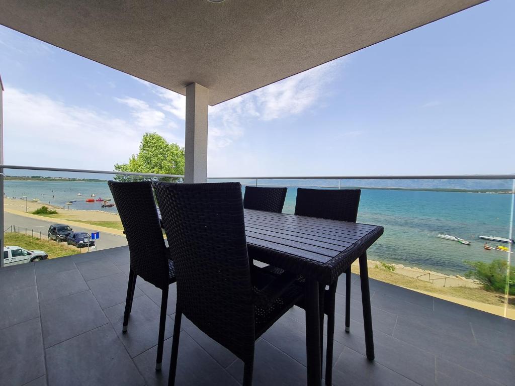 una mesa y sillas en un balcón con vistas al océano en Apartmani Adria en Nin