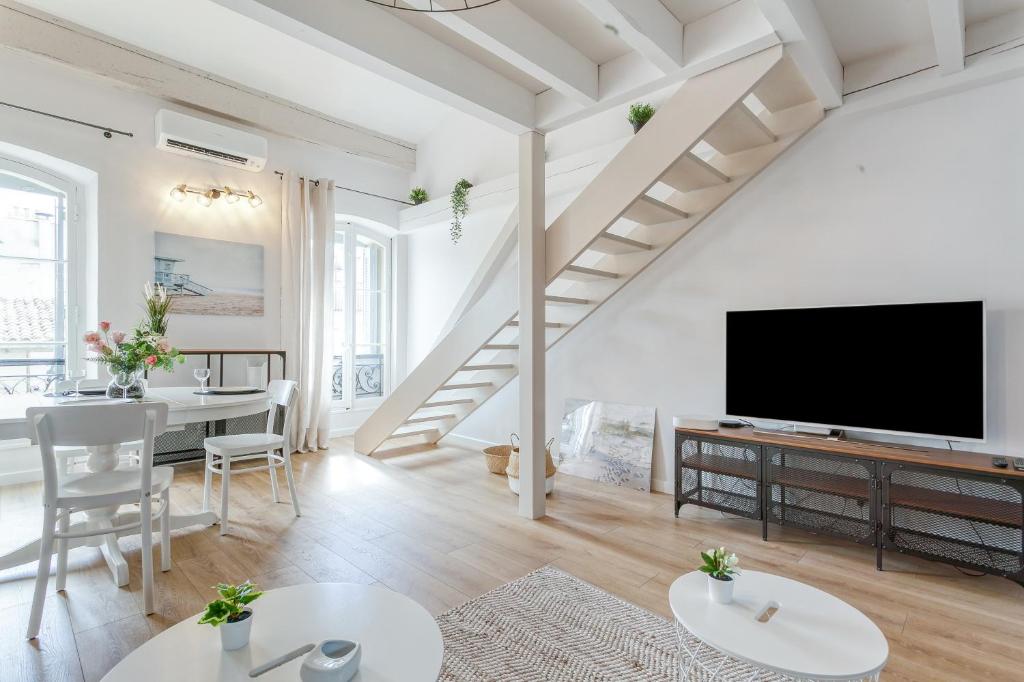 ein weißes Wohnzimmer mit einem großen TV und einem Tisch in der Unterkunft CMG - Marseille / Opéra in Marseille