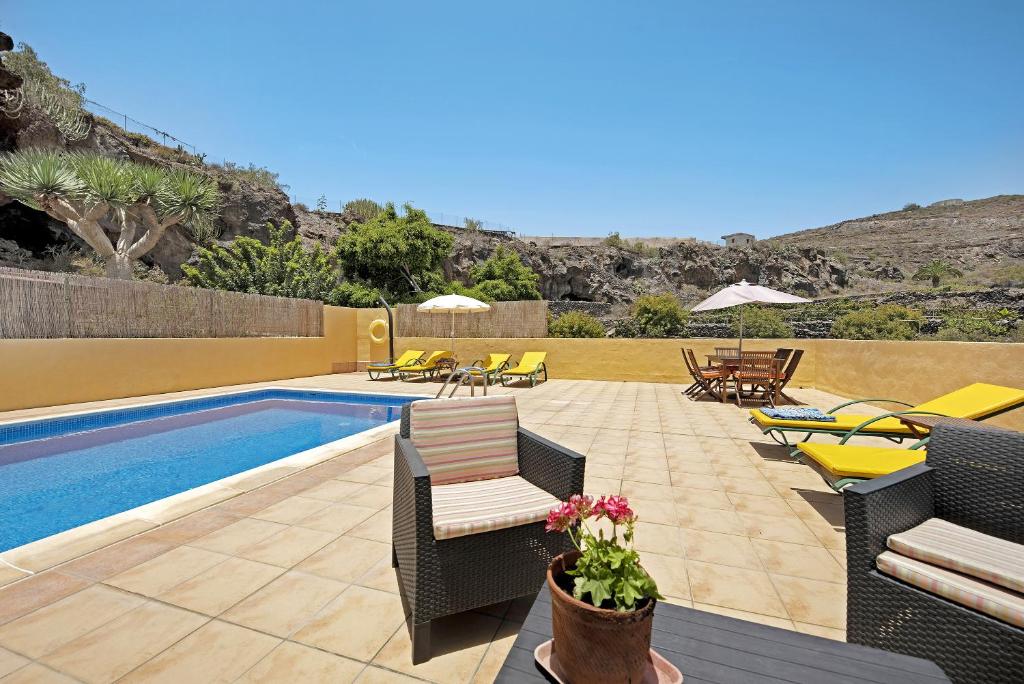 een patio met stoelen en een zwembad met een zwembad bij Finca Edén in Guía de Isora