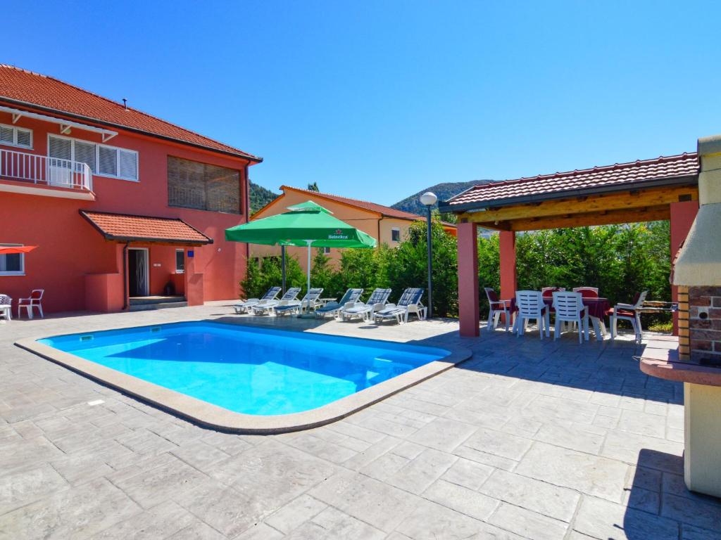 een patio met een zwembad en stoelen en een huis bij Apartment Baba Nevenka - MKA526 by Interhome in Vrgorac