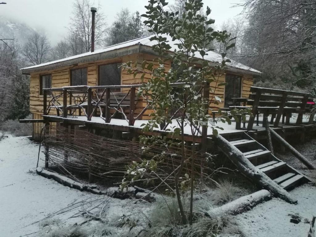 a log cabin in the snow with a porch at Cabaña La Chaura Conguillío in Melipeuco