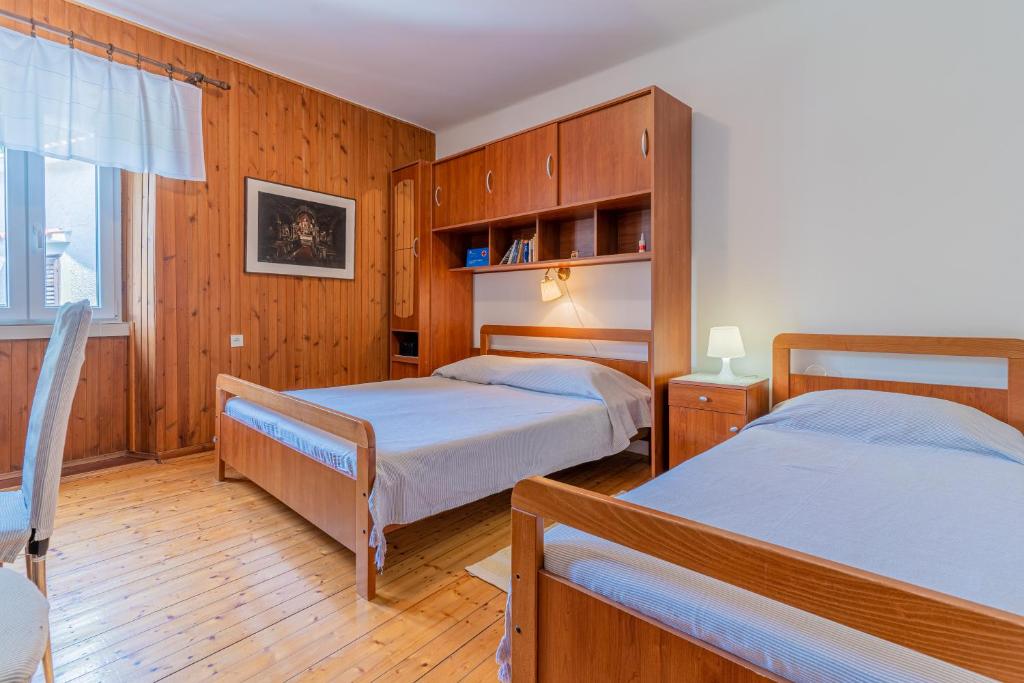 two beds in a room with wooden walls and wooden floors at Soba Cres in Cres