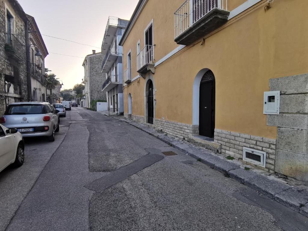 una strada vuota con auto parcheggiate sul lato di un edificio di Casa del Porto a Scario