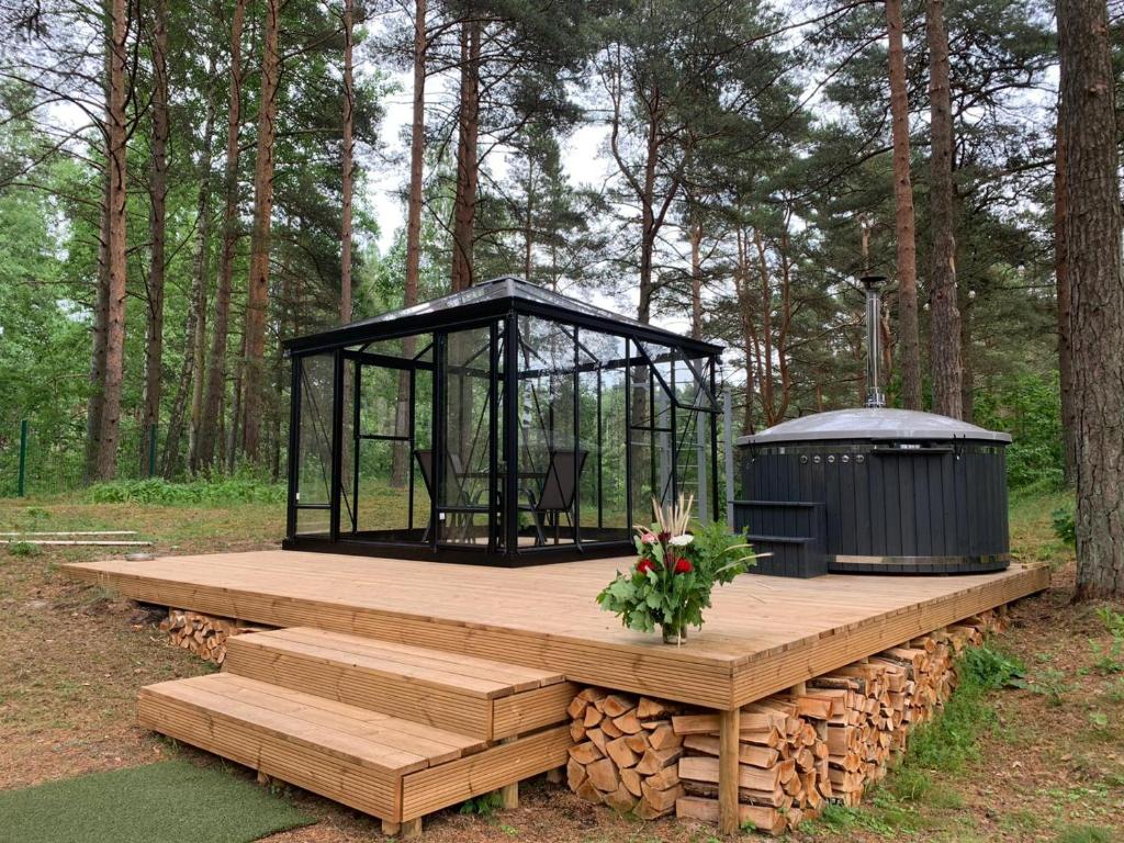 eine Holzterrasse mit einem schwarzen Pavillon im Wald in der Unterkunft Vallery Guest House in Bigauņciems