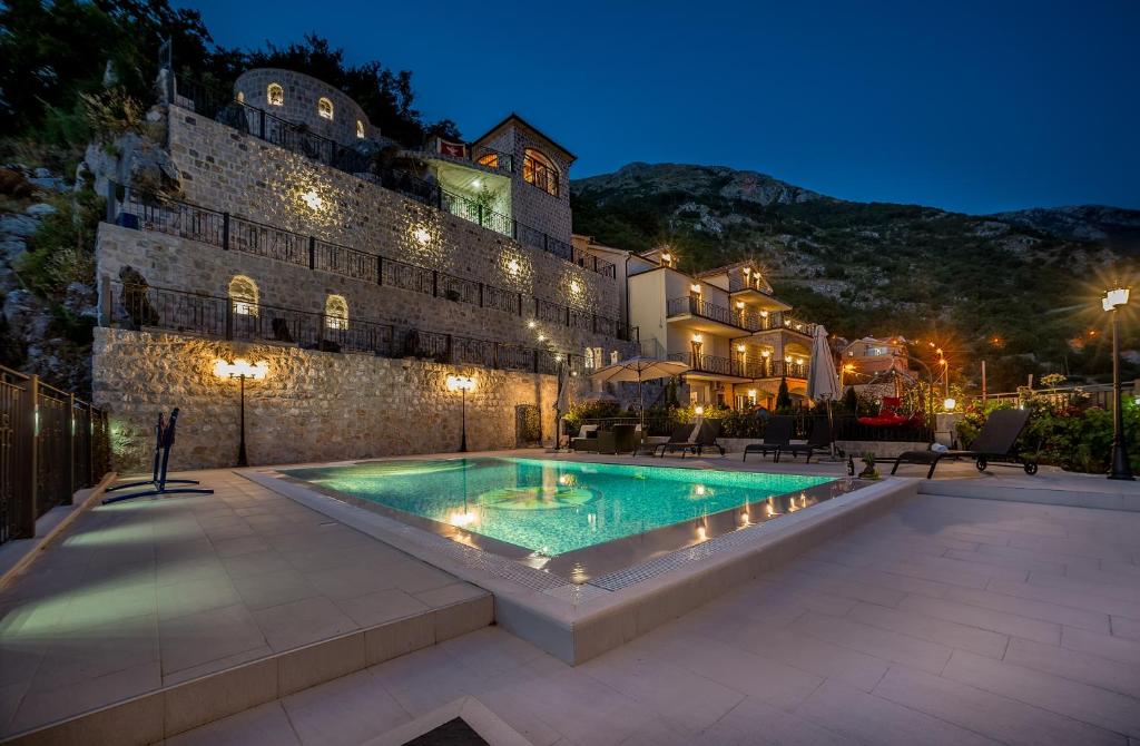 a swimming pool in front of a building at night at VILLA MILENA in Kotor