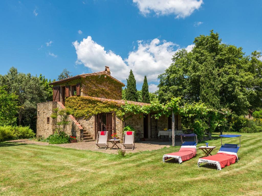 a stone house with chairs and a table in the yard at Holiday Home Ginestra by Interhome in Scansano