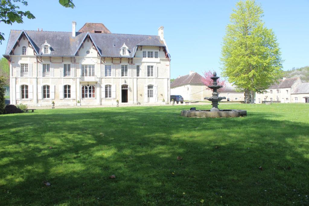 Une grande maison blanche avec une fontaine dans la cour dans l'établissement Château du Mesnil Soleil , gites et chambres d'hôtes, à Damblainville