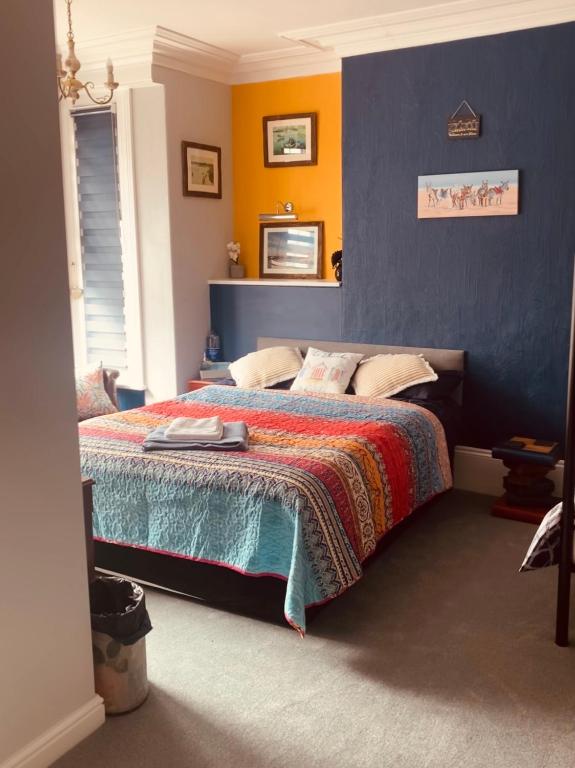 a bedroom with a bed with a blue and yellow wall at Greyfriars Guest House in Bridlington