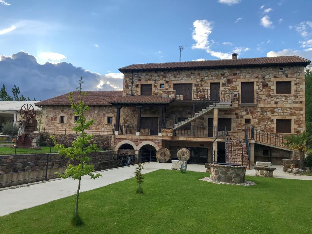 ein großes Steingebäude mit einem Rasen davor in der Unterkunft Apartamentos La Fabrica in Villaluenga de la Vega