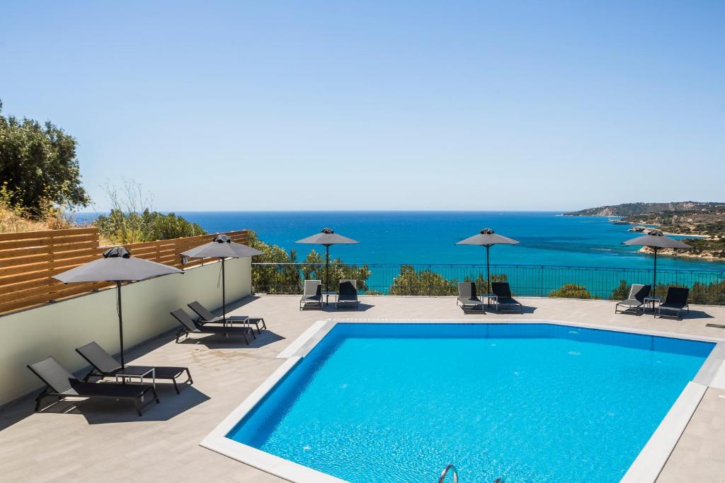 a view of a swimming pool with chairs and umbrellas at Afrato Village Sea View apartments in Trapezaki