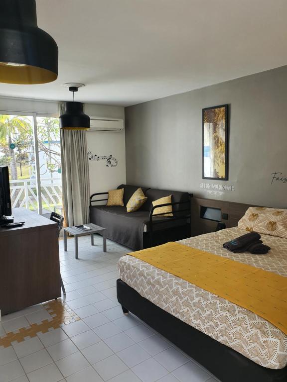 a hotel room with a bed and a couch and a living room at Le Petit Manganao in Saint-François