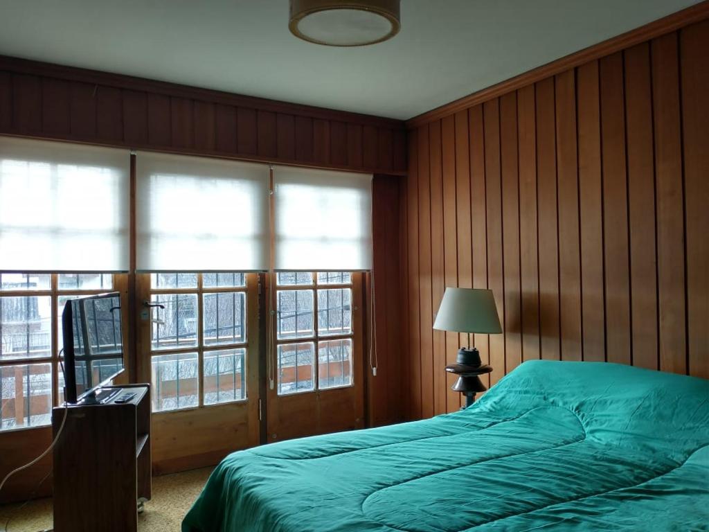 1 Schlafzimmer mit einem grünen Bett und 2 Fenstern in der Unterkunft MM in San Carlos de Bariloche