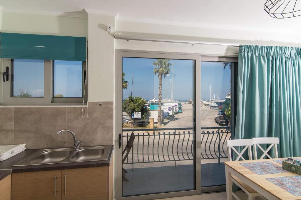 a kitchen with a balcony with a view of the ocean at Alexandra's Apartments - Port of Zante in Zakynthos Town