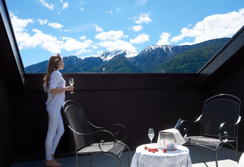 a girl standing on a balcony with a glass of wine at Hotel Residence der bircher in Campo di Trens