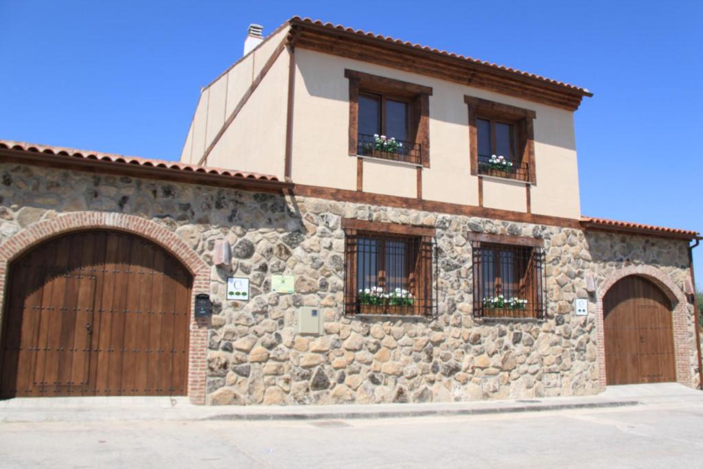 a stone building with two garage doors and windows at Casa Rural El Olivar de Valdefuentes in Valdefuentes