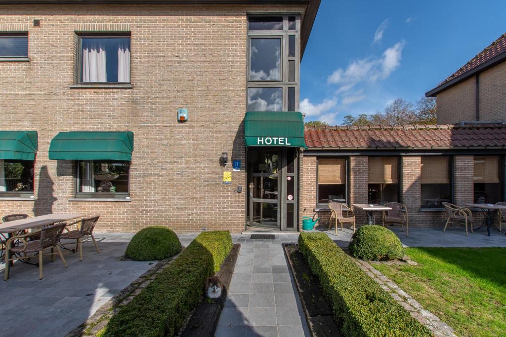 een hotel met tafels en stoelen voor een gebouw bij Hotel de Vaart in Damme