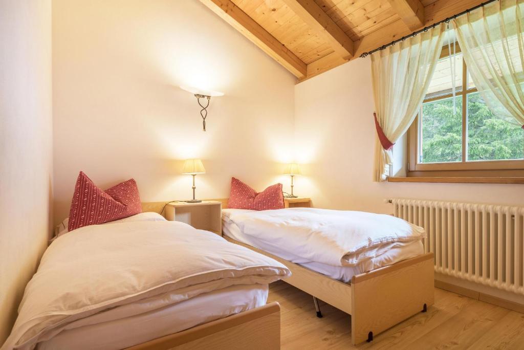 two twin beds in a room with a window at Chalet Crepes De Sela in Canazei