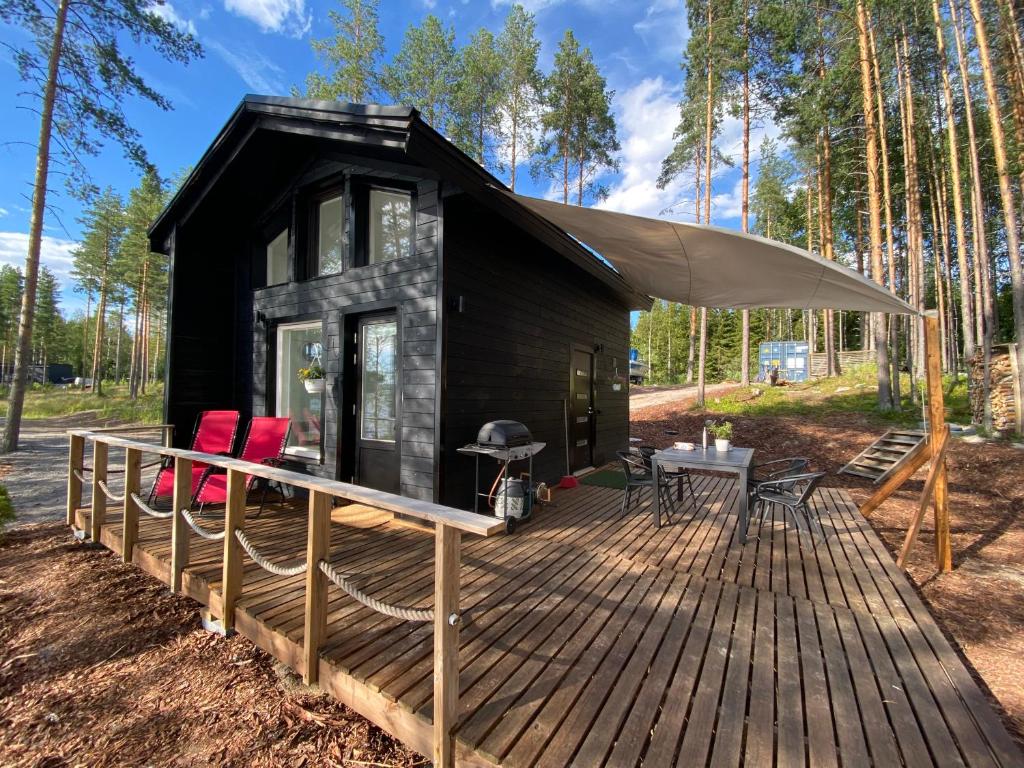 a black tiny house with a deck and a grill at Lakeland Cabins fi in Huopanankoski
