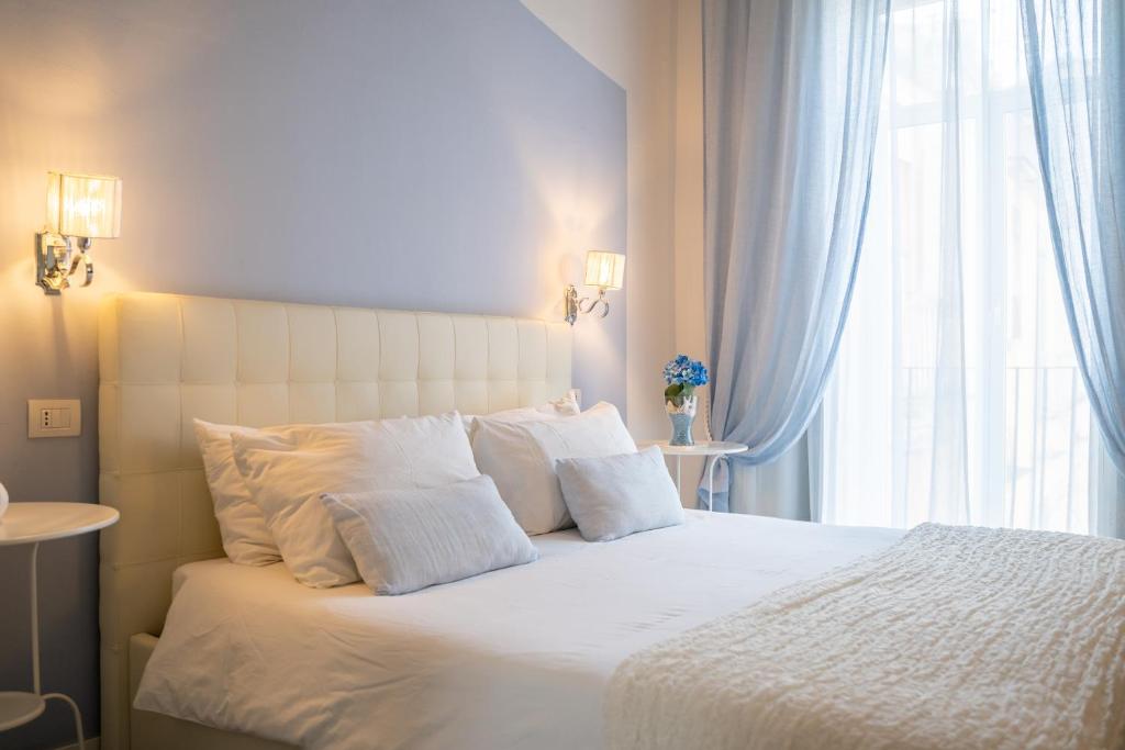 - une chambre avec un grand lit blanc et une fenêtre dans l'établissement Sotto le Stelle ai Decumani, à Naples