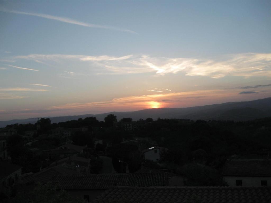 einen Sonnenuntergang über einer Stadt mit der Sonne am Himmel in der Unterkunft La Biocca in Poggio Murella