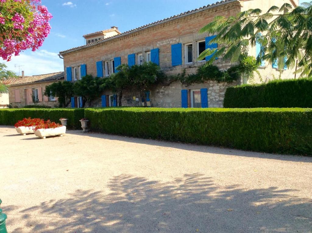 a building with blue windows and a hedge in front of it at LA DAME FINES in Puybegon