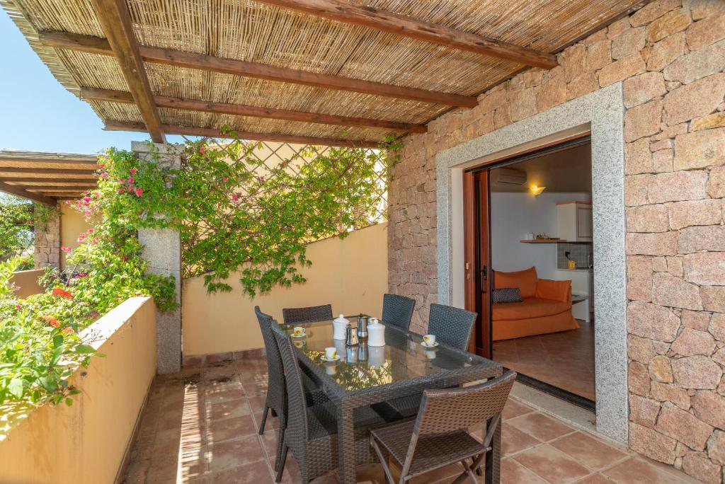 un patio con tavolo e sedie su un muro di mattoni di Villa Circe a Santa Teresa di Gallura