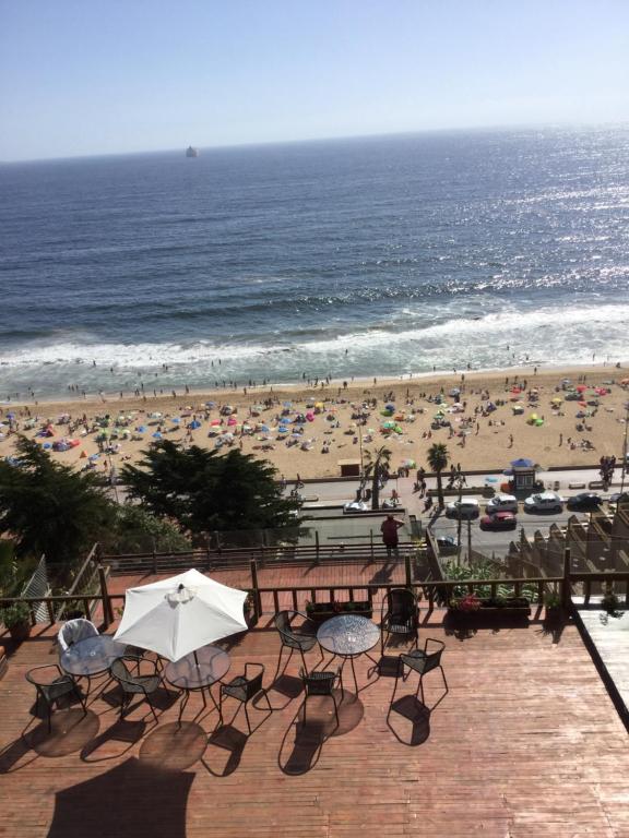 a view of a beach with chairs and an umbrella at Terrazas Del Mar in Viña del Mar