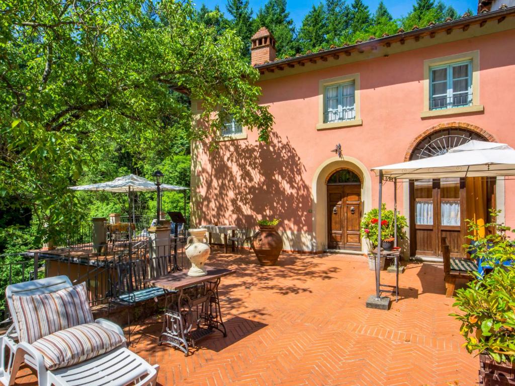 een huis met een patio met tafels en stoelen bij Holiday Home Il Mulinaccio by Interhome in Loro Ciuffenna