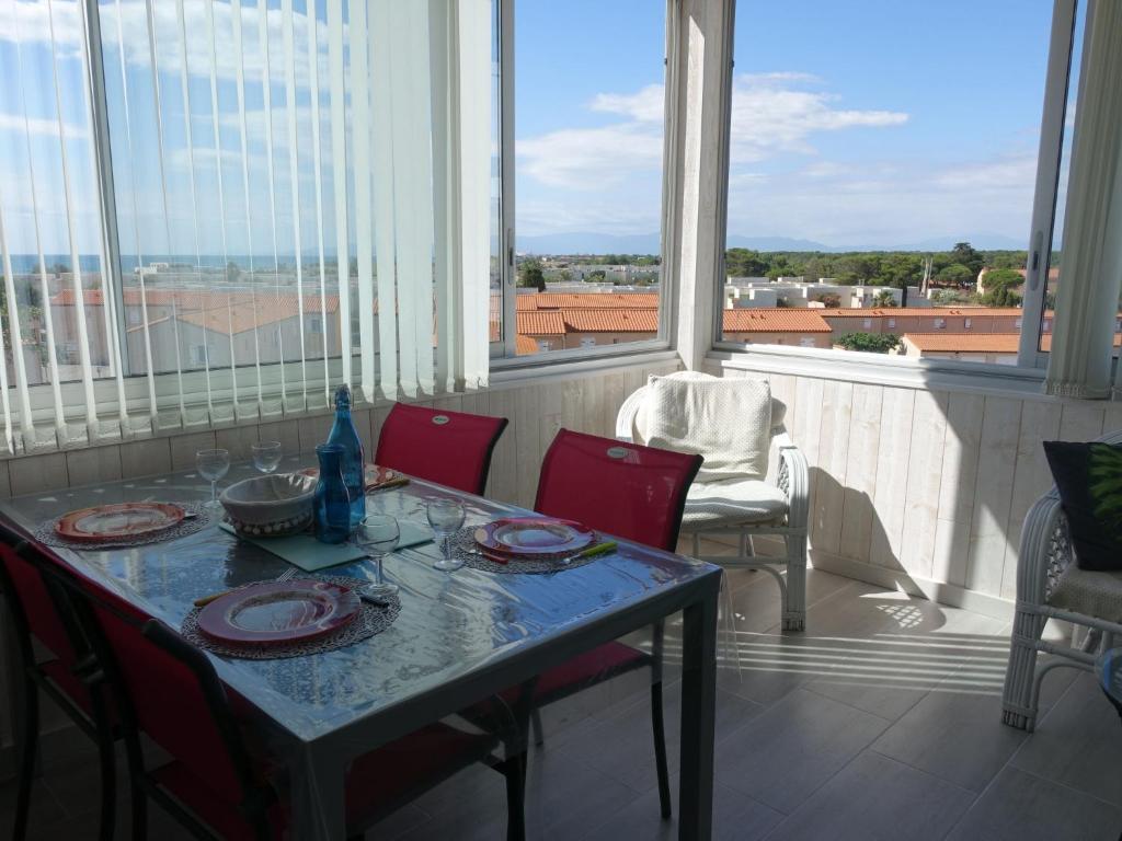 einen Tisch mit roten Stühlen und Blick auf einen Balkon in der Unterkunft Apartment Estany by Interhome in Le Barcarès