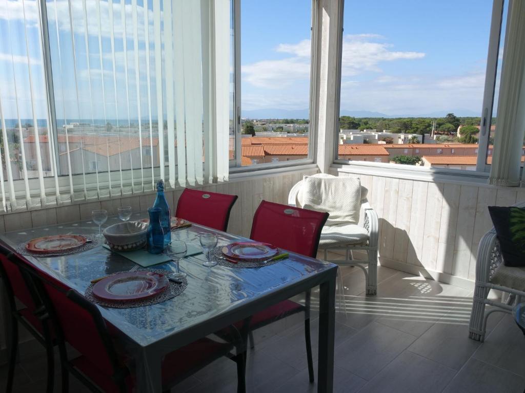 une table avec des chaises rouges et une vue sur un balcon. dans l'établissement Apartment Estany by Interhome, au Barcarès