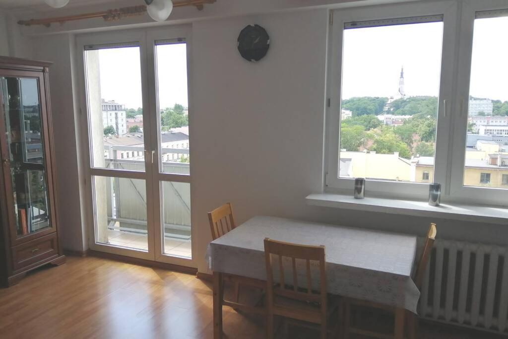 a dining room with a table and chairs and windows at Apartament z przepięknym widokiem w samym centrum in Częstochowa