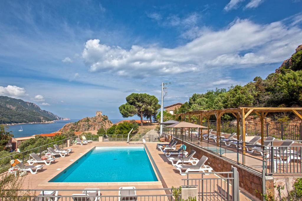 - une piscine avec des chaises longues et une vue sur l'eau dans l'établissement Hotel Kalliste, à Porto Ota