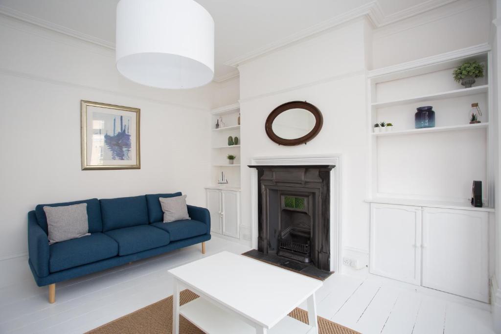 ein Wohnzimmer mit einer blauen Couch und einem Kamin in der Unterkunft York House - on a beach road, sleeps 12, with sea views in Worthing