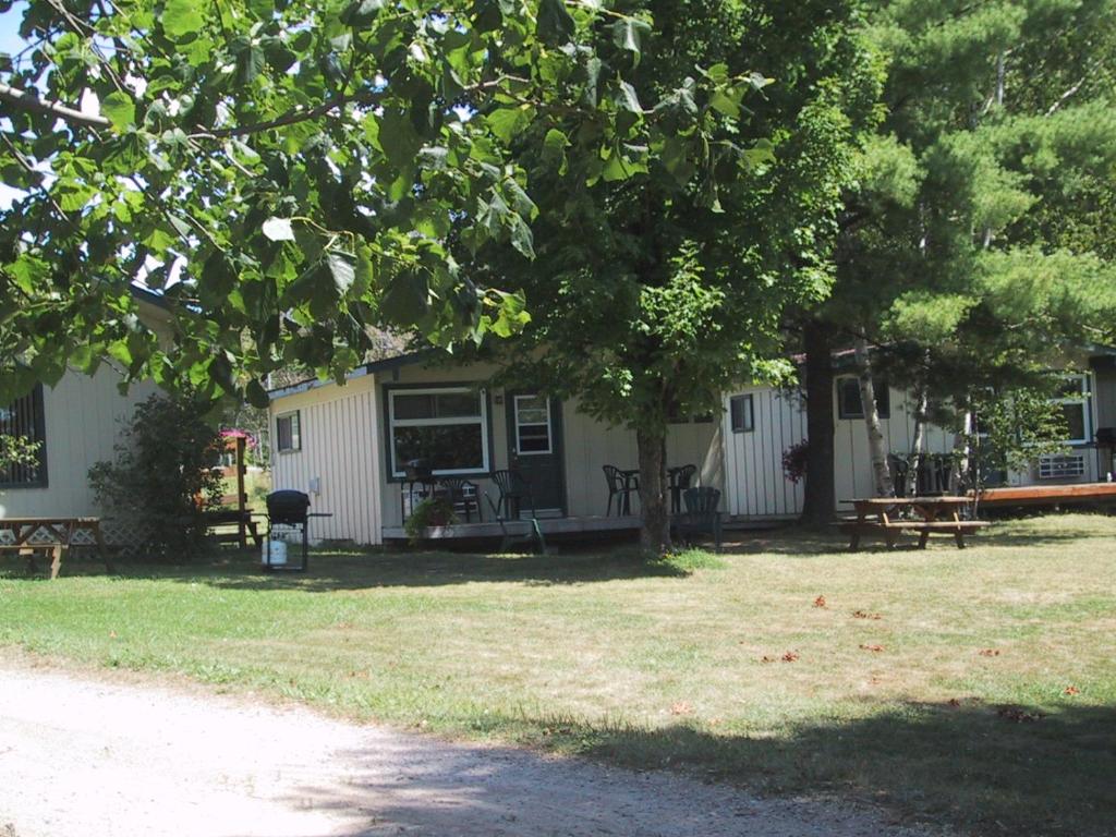 ein Haus mit Picknicktischen und Bänken in einem Hof in der Unterkunft Colonial Bay Motel and Cottages in Huntsville