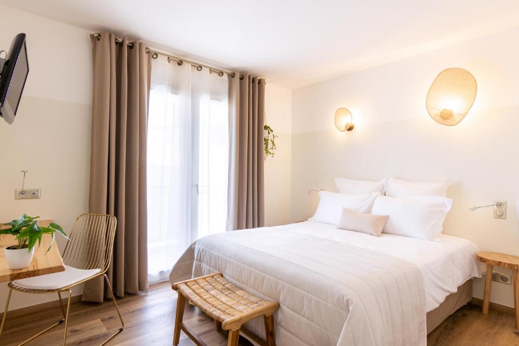 a bedroom with a large white bed and a desk at Hôtel Flor in Saint-Florent