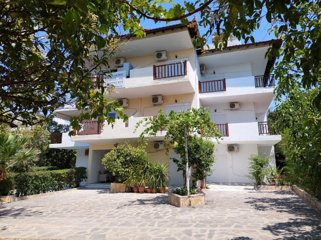 a large white building with trees in front of it at Lelegianni Studios and Apartments in Psakoudia