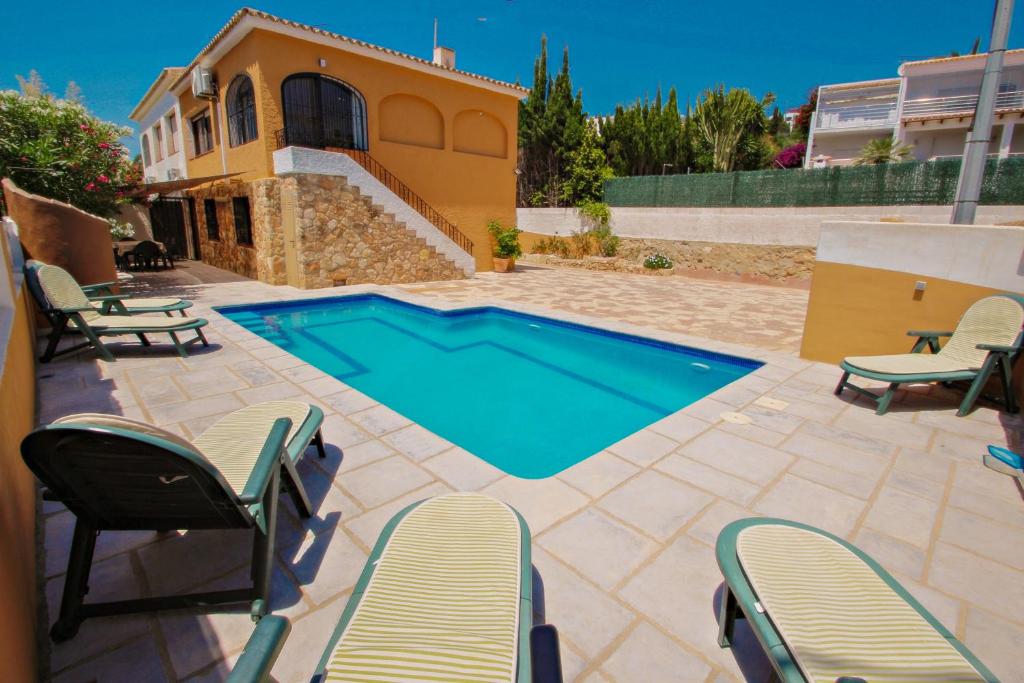 uma piscina num pátio com cadeiras e uma casa em Basetes - holiday home with private swimming pool in Calpe em Calpe