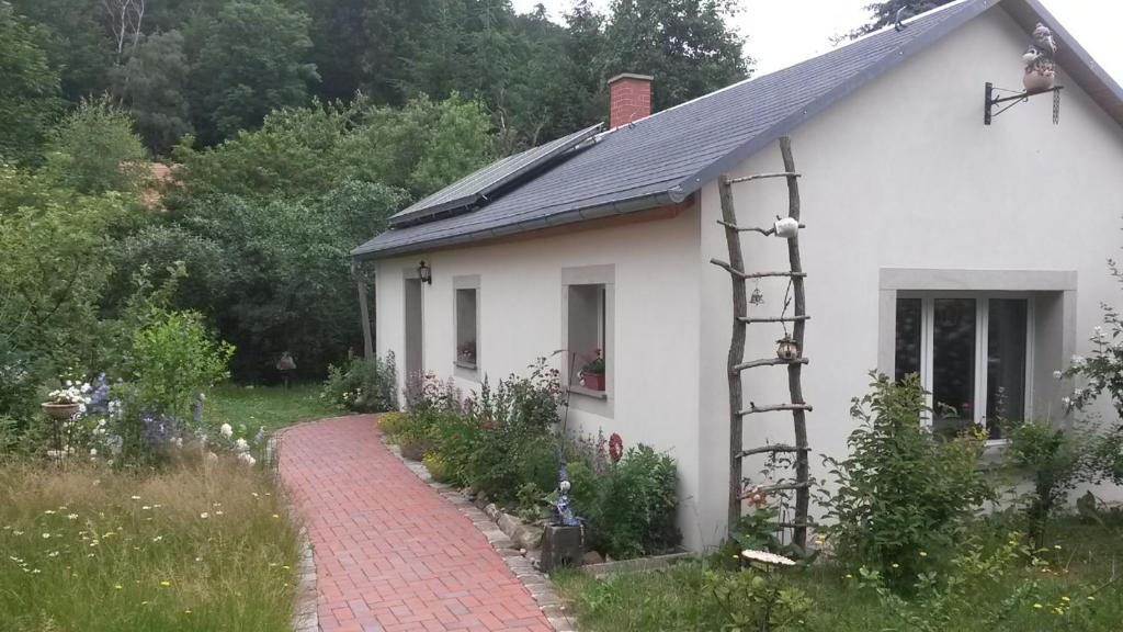 ein kleines weißes Haus mit einem Backsteinweg daneben in der Unterkunft Pochebachhäusl in Kurort Jonsdorf