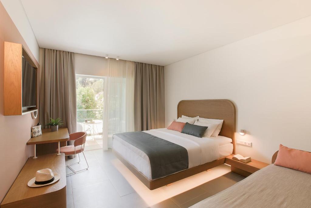 a hotel room with a bed and a window at Mandraki Village Boutique Hotel in Koukounaries